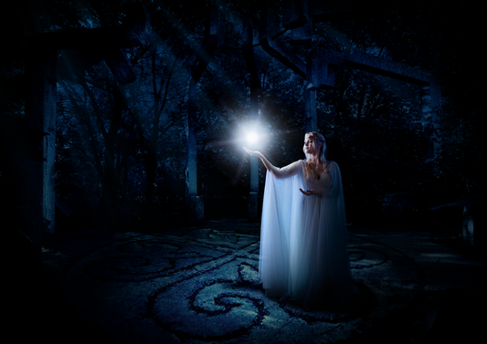A femme presenting person in a white dress casting a magical spell in the form of a white orb of magic.